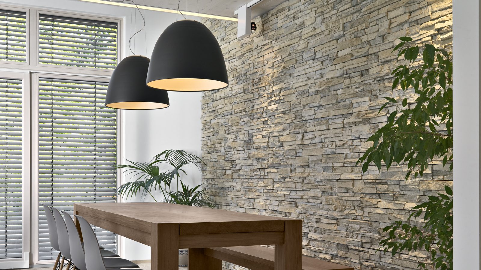 A dining room with a stacked stone feature wall running floor to ceiling