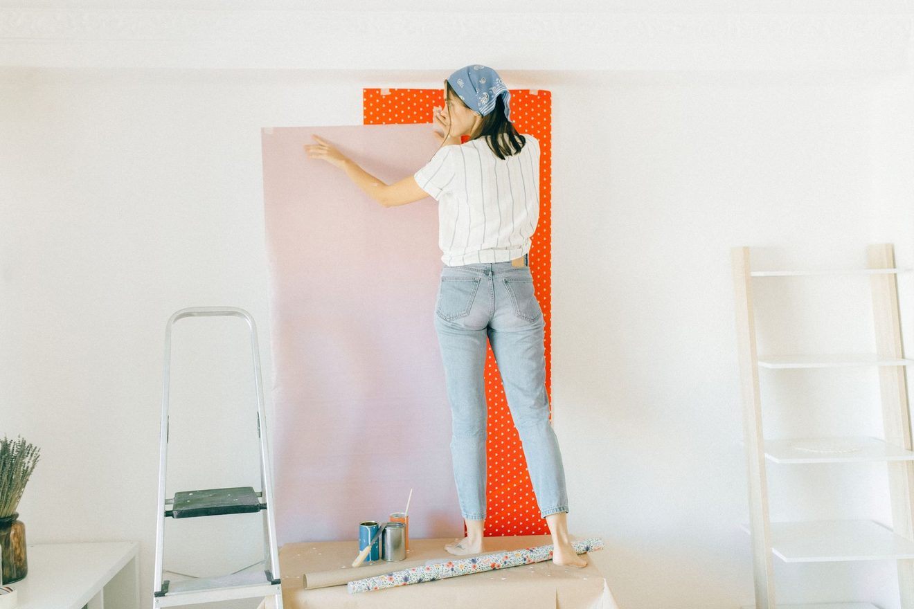 A person smoothing a strip of wallpaper onto a wall