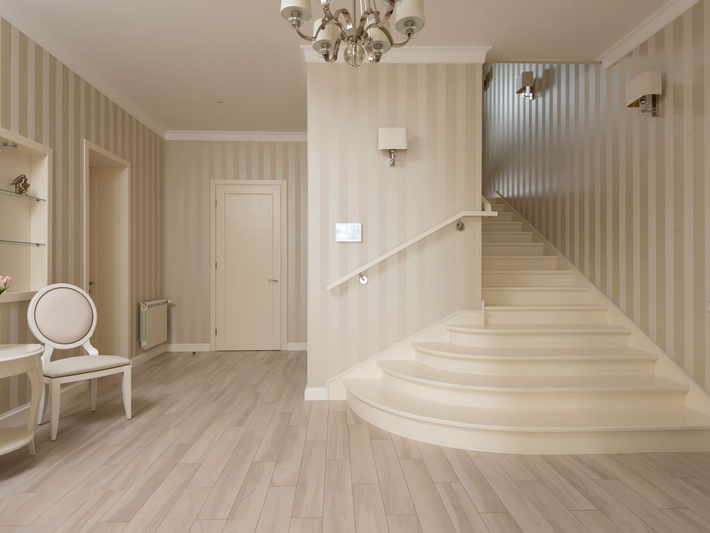A bright entryway with striped wallpaper and a curved staircase