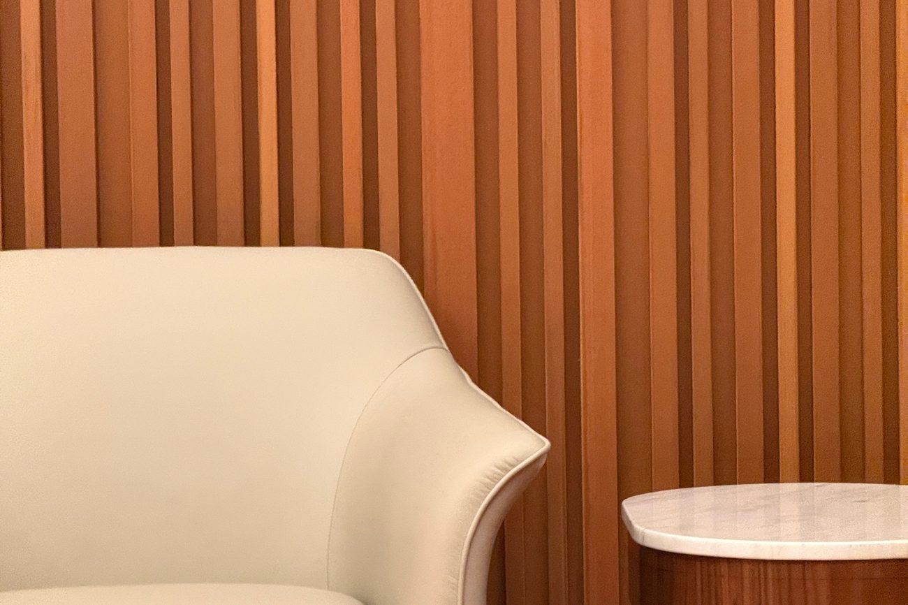 Close-up of warm-toned vertical wood slats beside a cream armchair